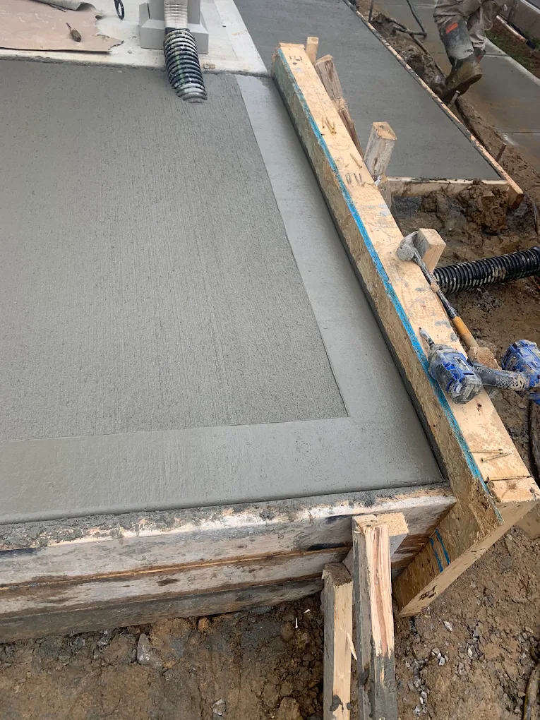 Fresh concrete pour inside wood forms with tools on the form boards