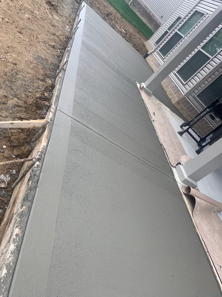 Freshly poured concrete patio beside a house porch